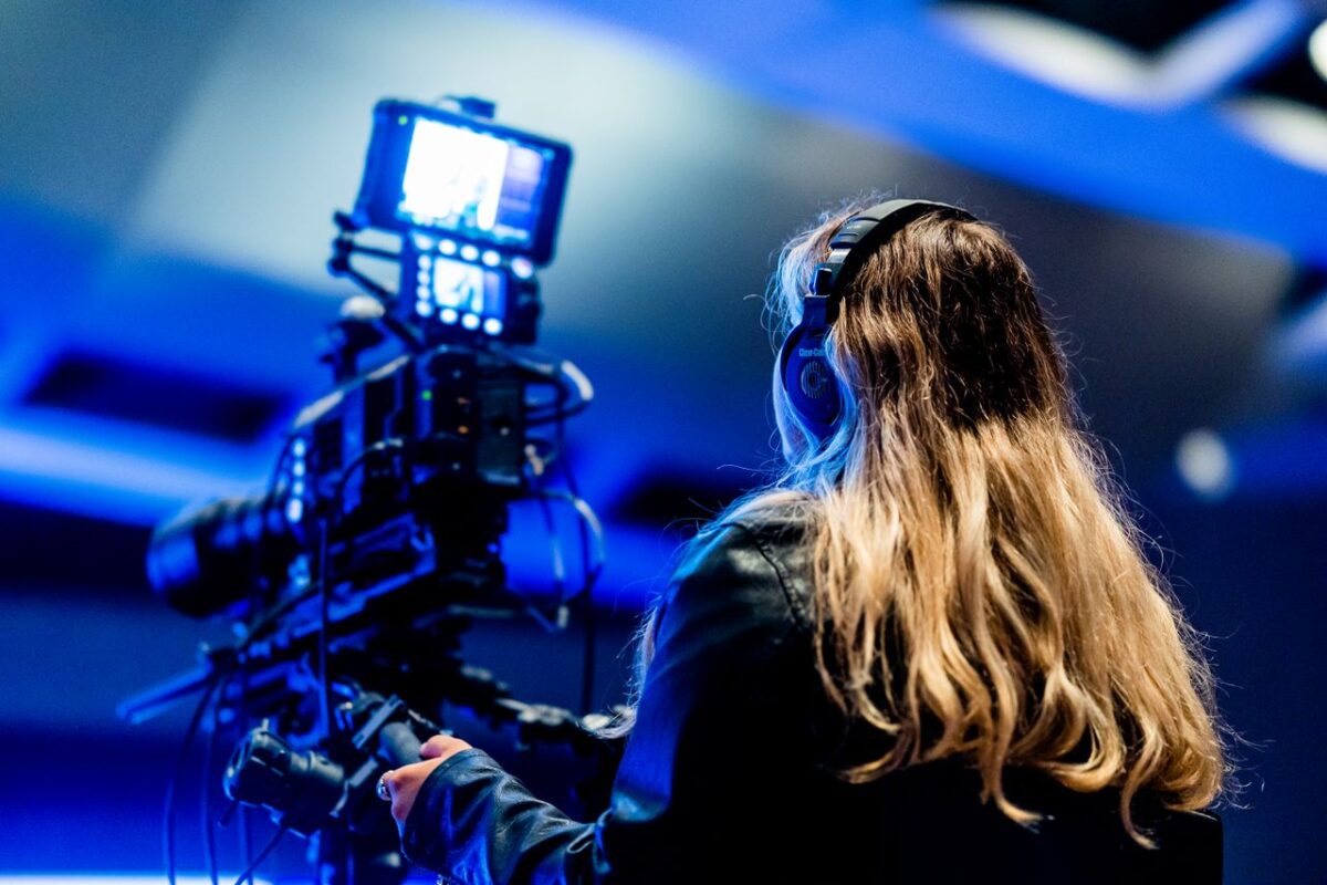 À propos A cameraperson using professional equipment indoors for filming. High-tech setup.