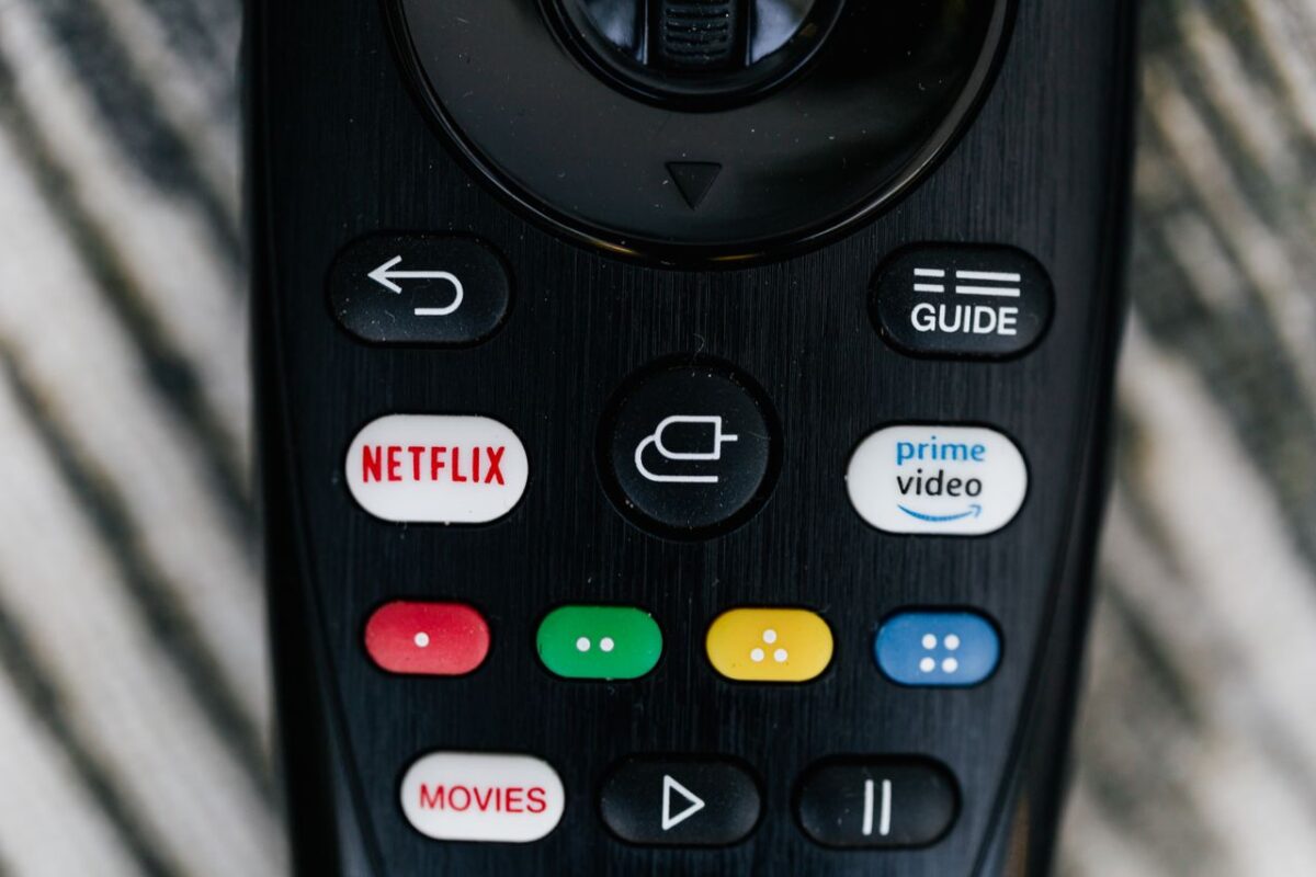 À propos Detailed close-up image of a TV remote control with streaming service buttons.