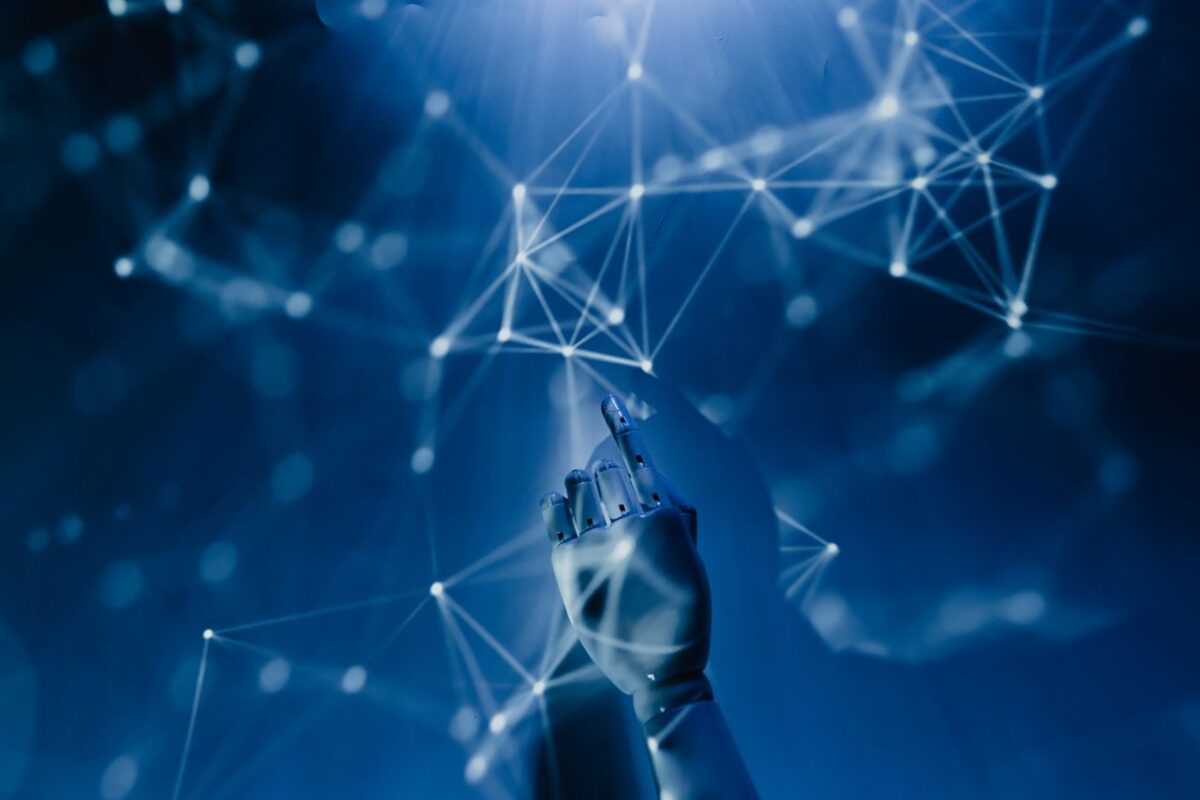 gallery-02 A robotic hand reaching into a digital network on a blue background, symbolizing AI technology.